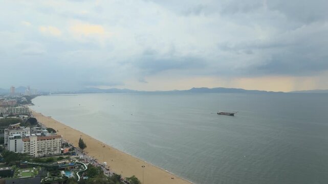 Aerial view of Pattaya beach and sea during cloudy weather before tropical storm, Thailand. Drone shot of coastal cityscape, sandy shoreline and dramatic storm clouds over the ocean, seascape concept.