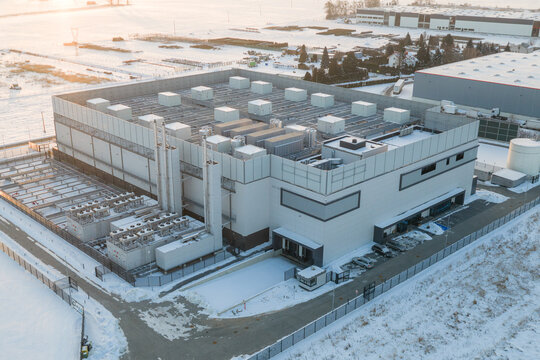 Aerial view of an advanced AI data center featuring cooling units on the roof and surrounding snow-covered grounds in Warsaw, Masovian Voivodeship, Poland.