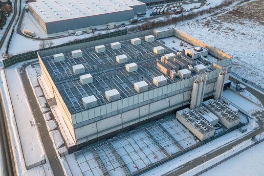 Aerial view of an advanced AI data center with cooling units on the roof, surrounded by snow-covered grounds in Warsaw, Masovian Voivodeship, Poland.