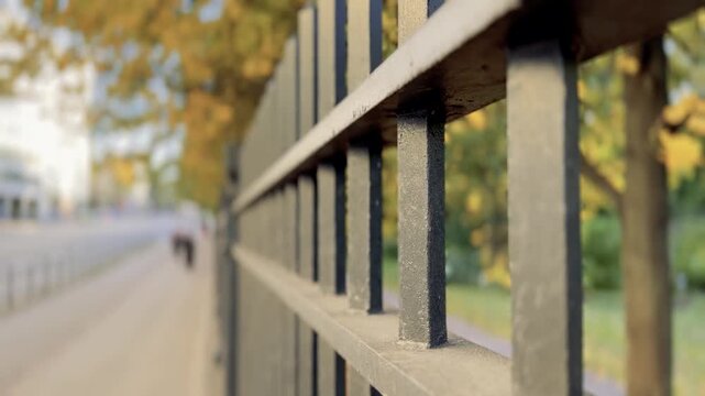 Iron fence Beside an Autumn Park Path With Walkers