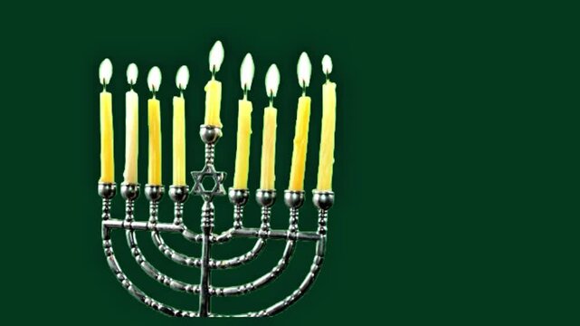 Traditional silver Hanukkah menorah with burning candles featuring the Star of David on a dark green background. 