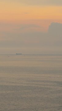 Peaceful sunset over the sea with distant boats and hazy sky in Pattaya, Thailand