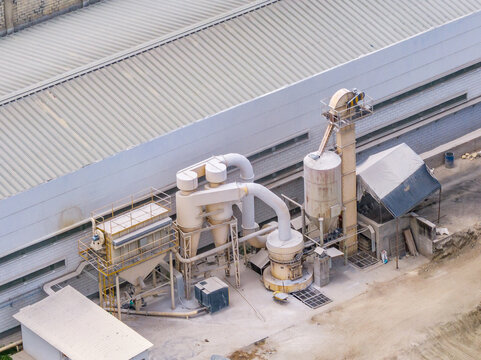 Aerial view of Tello Oil Field petroleum processing facilities featuring industrial silos, pipes, and machinery next to a large warehouse in Colombia.