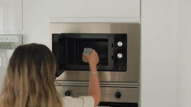 Person heating infant formula in microwave oven