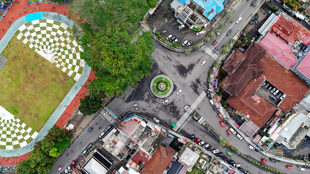 Aerial view of Taman Kota Lapang Merdeka Sukabumi featuring a checkered sports field, a central roundabout, urban buildings, and roads with traffic in Sukabumi, West Java, Indonesia.