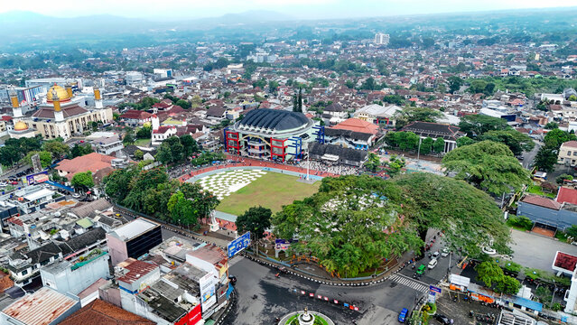Aerial view of Taman Kota Lapang Merdeka Sukabumi featuring a central green field, surrounding urban rooftops, and a mosque with a golden dome in Sukabumi, West Java, Indonesia.