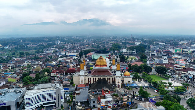 Aerial view of Masjid Agung Kota Sukabumi with its golden dome and minarets, surrounded by the dense urban landscape of Sukabumi, West Java, Indonesia.