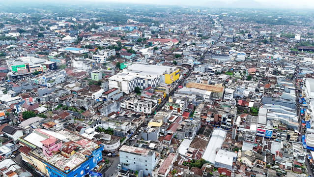 Aerial view of the dense urban landscape of Sukabumi, featuring a mix of commercial buildings, residential rooftops, and narrow streets in Sukabumi, West Java, Indonesia.