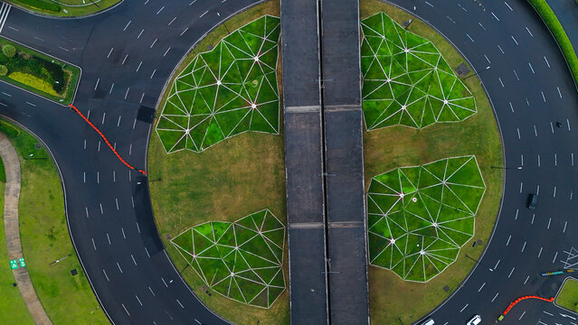 Aerial view of Bunderan Summarecon Bandung, a modern roundabout with geometric green spaces and a central bridge structure in Gedebage, West Java, Indonesia.