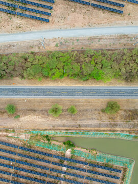 Aerial view of the Puerta de Oro solar park featuring extensive rows of photovoltaic panels, a paved road, a line of trees, and a small pond in Guaduas, Cundinamarca, Colombia.
