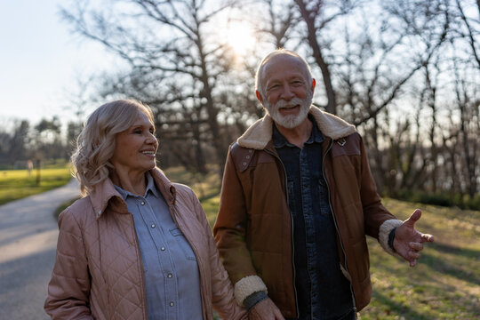 Cheerful senior couple enjoying an outdoor walk together in a sunny park, representing active aging, physical wellbeing and a healthy retirement lifestyle
