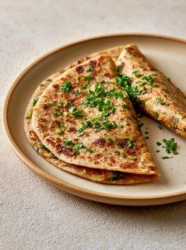 Plate with three flatbreads on it. the flatbread is golden brown in color and appears to be freshly cooked. it is garnished with chopped parsley, which is a bright green color.
