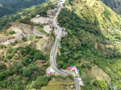 Aerial view of the winding road connecting Villeta and Guaduas, surrounded by lush green mountains and dense tropical vegetation in the Andean landscape, Villeta, Cundinamarca, Colombia.