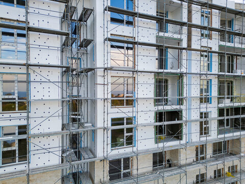 Building facade thermal insulation work with scaffolding on apartment house