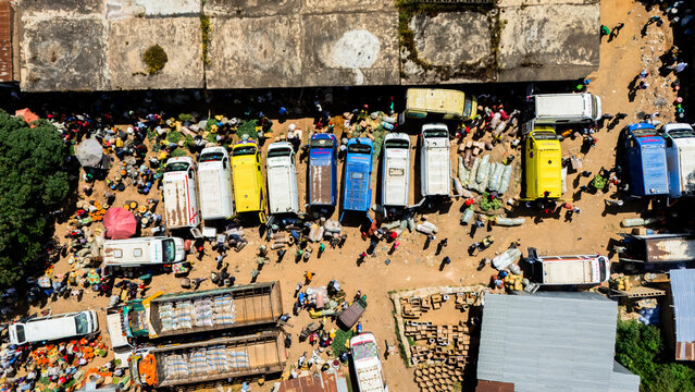 Aerial view of the busy Building Materials Market with numerous parked vans and trucks, vendors, and shoppers navigating the crowded area in Jos, Plateau, Nigeria.