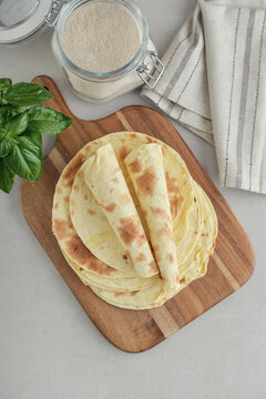 Stack of lavash or chapati flatbreads on a wooden cutting board