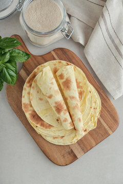 Stack of lavash or chapati flatbreads on a wooden cutting board