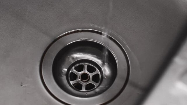 Close-up of a sink drain.
Water drains into the sewer.