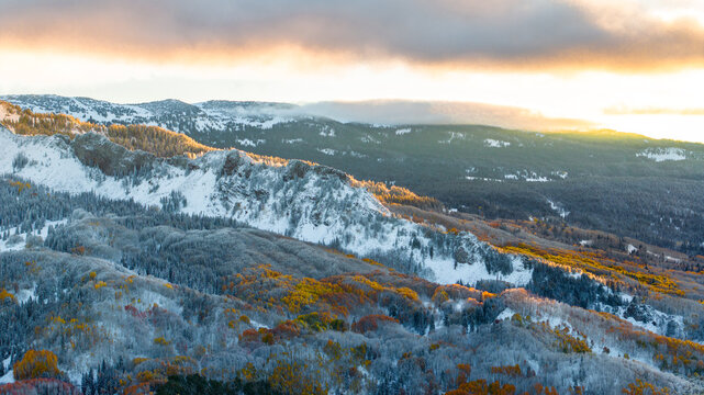 Aerial view of Kebler Pass and Marcellina Mountain in autumn, featuring snow-dusted aspen forests with vibrant fall foliage under a sunrise sky in Crested Butte, Colorado, United States.