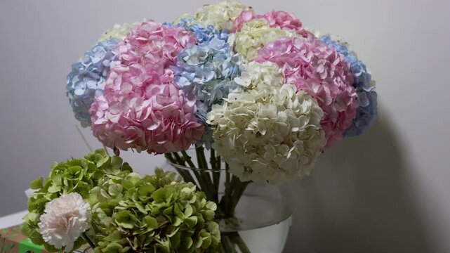A large bouquet of multicolored hydrangeas in a vase on the table.