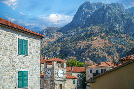The famous Clock Tower in Arms Square (Trg od Oružja), in the medieval city of Kotor (UNESCO), Montenegro. In the background, the high, rocky mountains surrounding the Bay of Kotor (Boka Kotorska).