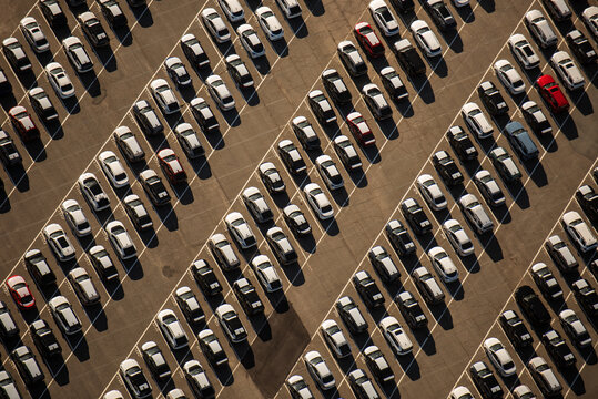 Aerial view of a large parking lot filled with numerous cars parked in diagonal rows under golden hour sunlight in Vallejo, California, United States.