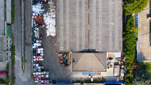 Aerial view of a waste processing facility with sorted materials in containers and piles of recyclables on the concrete yard in Milan, Lombardy, Italy.