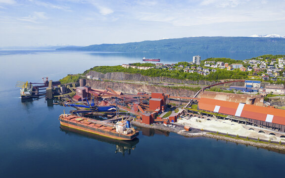 Aerial view of Narvik Harbor with industrial iron ore loading facilities, large cargo ships docked at the pier, and the town of Narvik Narvik, Nordland, Norway.