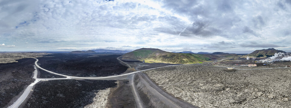 Aerial view of Sundhnukur Volcano surrounded by vast solidified black lava fields, winding roads, and geothermal infrastructure in Grindavik, Grindavikurbaer, Iceland.