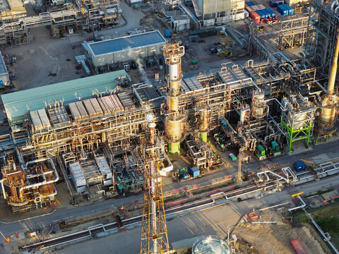 Aerial view of an oil refinery with complex industrial infrastructure, tall distillation towers, metal piping networks, and storage tanks in the United Kingdom.