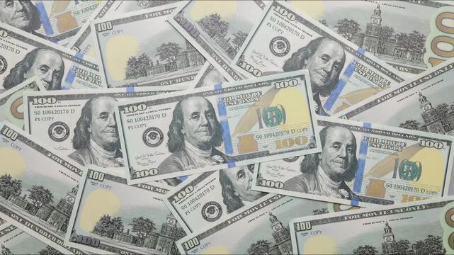 Hundred dollar bills accumulate to fill the background