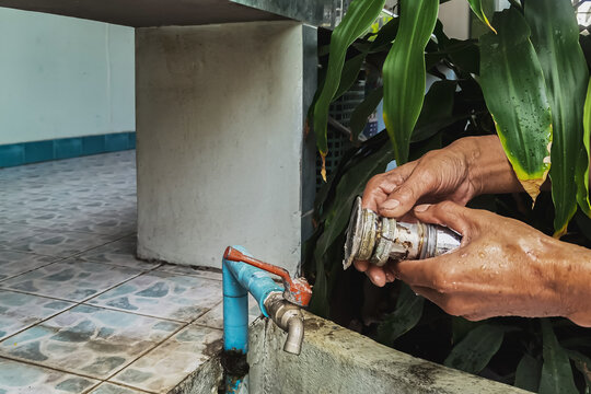 Clogged sink pipe in hands ,A plumber cleans a clogged siphon pipe of a sink in the kitchen. Clogged rusty water trap siphon and drainage pipe cleaning. Home plumbing maintenance service. DIY concept