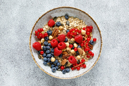 Healthy breakfast bowl with oatmeal muesli fresh berries raspberries blueberries nuts and red currants