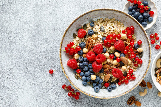Healthy breakfast bowl with oatmeal muesli fresh berries raspberries blueberries nuts and red currants