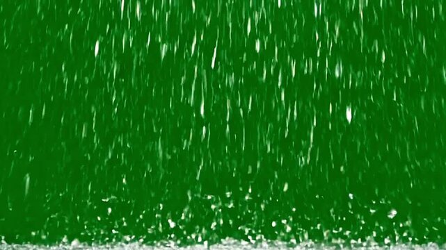 Heavy rain falling against vibrant green background chroma key video footage effect