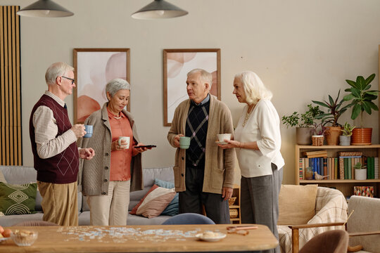 Diverse senior group talking and drinking coffee in community club. Image suitable for retirement living, senior care services, and elderly socializing campaigns