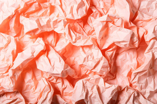 Crumpled paper texture close up in coral and blush pink tones
