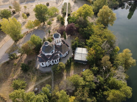 Aerial view of St. Prophet Elijah Church surrounded by lush trees and greenery next to a lake in the Drujba district, Sofia, Sofia City Province, Bulgaria.