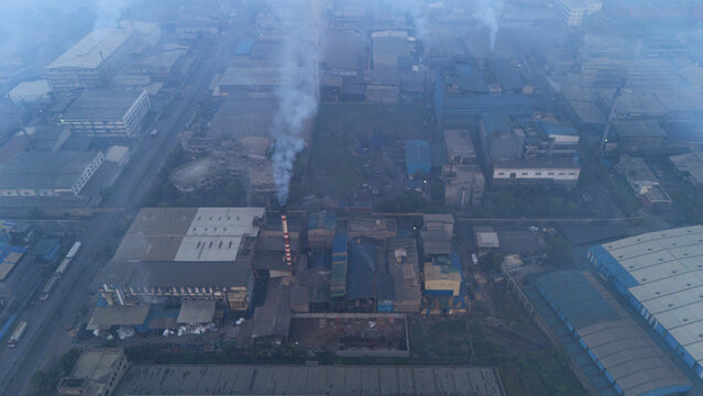 Aerial view of the Sachin industrial area in Surat, featuring factory buildings, smoking chimneys, and surrounding urban infrastructure in Surat, Gujarat, India.