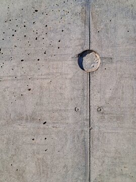 Weathered concrete wall texture featuring a vertical formwork seam, screw marks, and a circular recessed mark.