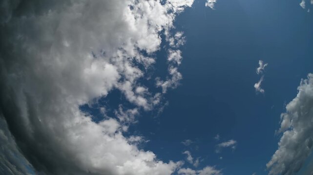 Time lapse of white and grey summer clouds in a fish-eye summer view of the blue sky
