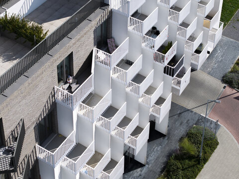 Aerial view of modern apartment building with staggered white balconies and brick facade, Krakow, Lesser Poland Voivode, Poland.