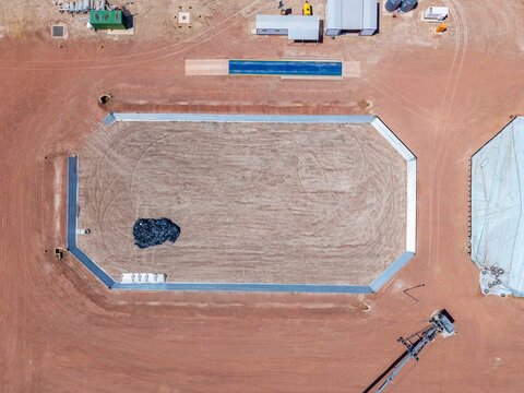 Aerial view of an industrial reservoir with metal walls surrounded by red earth, construction equipment, and storage containers in Philadelphia, Western Cape, South Africa.
