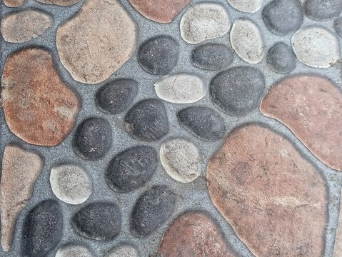 Top view of textured stone tile floor with colorful pebbles and rocks, suitable for background, paving, or architecture design.