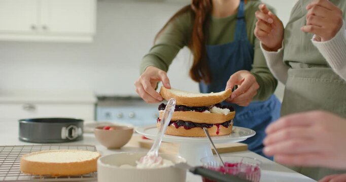 Diverse women in kitchen lifting sponge from cooling rack and aligning on turntable, finishing cake