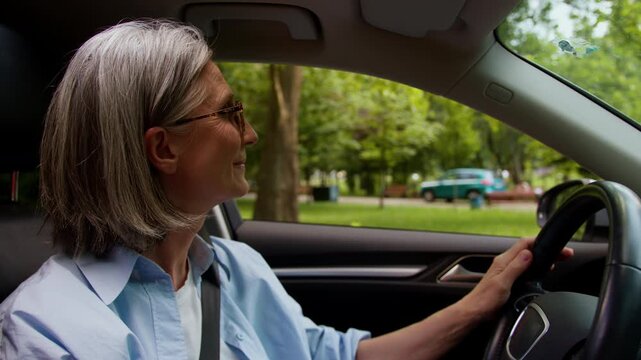 Cheerful joyful Caucasian grandmother old woman driving luxury own rental car in city smiling senior aged female elderly lady working courier deliver taxi driver test drive auto owner in automobile