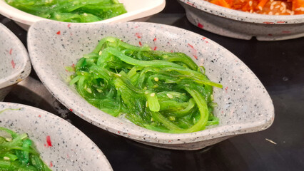 seasoned green seaweed salad chuka wakame with sesame seeds in small oval dish Japanese appetizer food  © Rungphailin