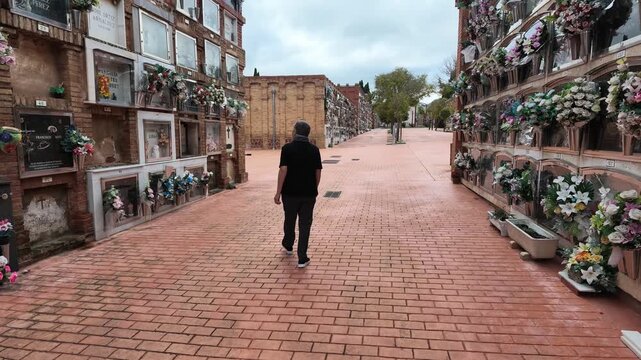 Man walking alone in a cemetery visiting graves