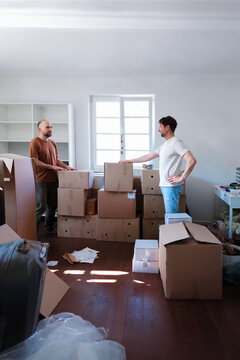 Friends Packing Boxes While Moving Into New Apartment