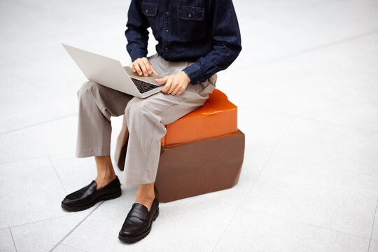 Person Working on Laptop While Sitting on Cube Seating